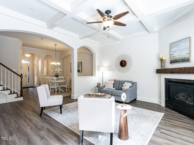 living area with baseboards, arched walkways, coffered ceiling, stairway, and wood finished floors