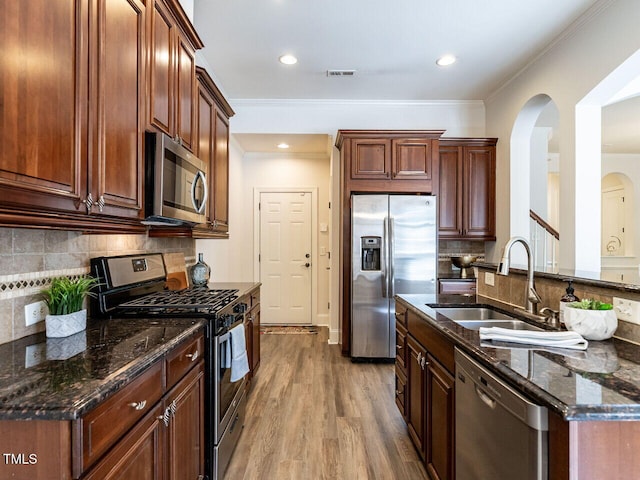 kitchen with visible vents, appliances with stainless steel finishes, ornamental molding, a sink, and wood finished floors