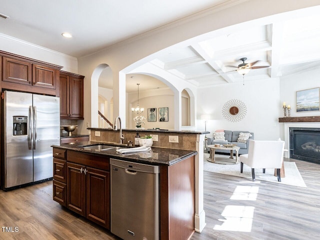 kitchen with coffered ceiling, a glass covered fireplace, open floor plan, stainless steel appliances, and a sink