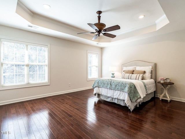 bedroom with a raised ceiling, visible vents, baseboards, and hardwood / wood-style floors