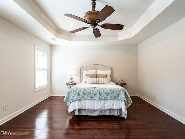 bedroom featuring ornamental molding, a tray ceiling, baseboards, and hardwood / wood-style flooring