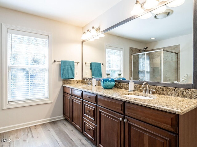 full bathroom featuring wood finished floors, a sink, a shower stall, and double vanity