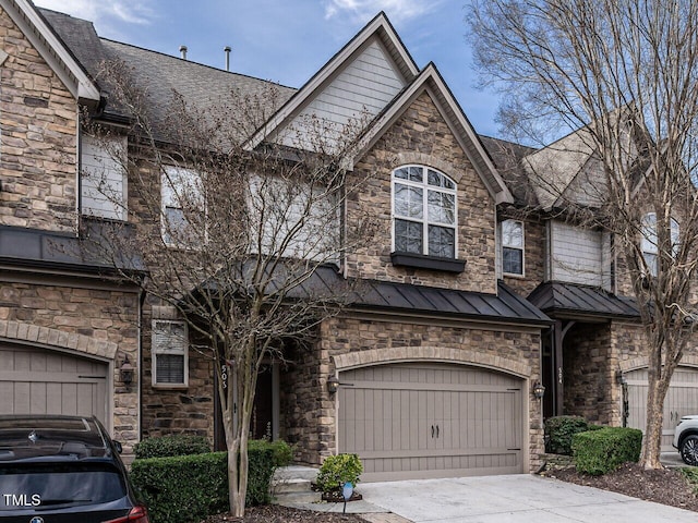 view of property featuring metal roof, a standing seam roof, an attached garage, and driveway