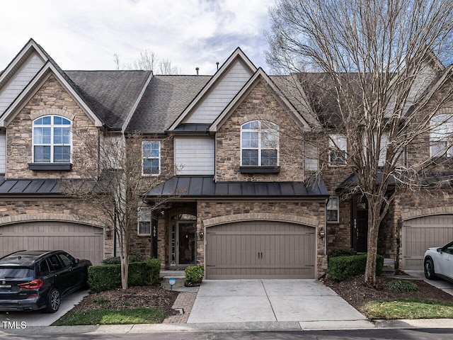 view of front of home with metal roof, an attached garage, driveway, roof with shingles, and a standing seam roof