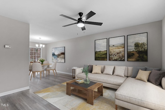 living area with baseboards, wood finished floors, and ceiling fan with notable chandelier