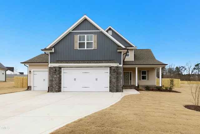 craftsman-style house featuring stone siding, fence, and concrete driveway