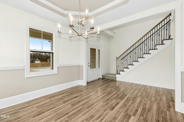 foyer with wood finished floors, baseboards, stairway, a tray ceiling, and crown molding