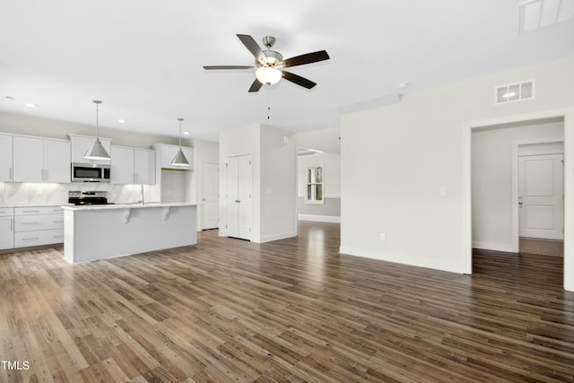 unfurnished living room with visible vents, ceiling fan, baseboards, and wood finished floors