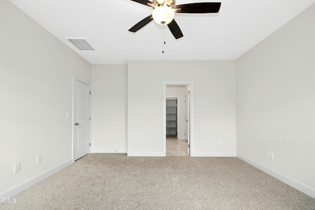 unfurnished bedroom with baseboards, visible vents, a walk in closet, and light colored carpet