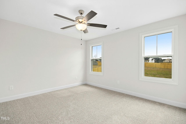 empty room featuring light carpet, visible vents, baseboards, and a ceiling fan