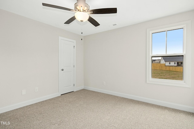 empty room featuring light carpet, visible vents, baseboards, and a ceiling fan