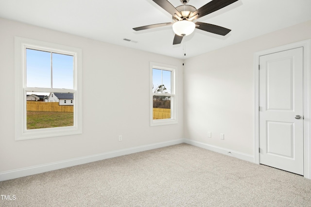 carpeted spare room with baseboards, visible vents, and a ceiling fan