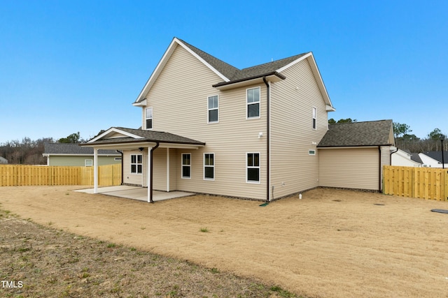 back of property with a shingled roof, a patio area, and fence