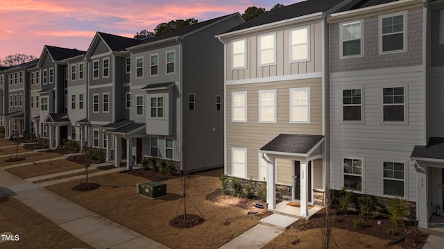 townhome / multi-family property featuring stone siding, a residential view, and board and batten siding