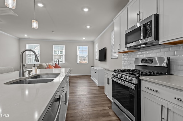 kitchen with appliances with stainless steel finishes, tasteful backsplash, a sink, and ornamental molding