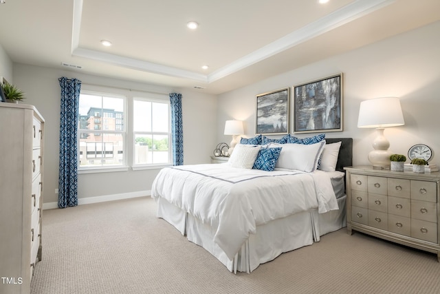 bedroom with a tray ceiling, recessed lighting, visible vents, light carpet, and baseboards
