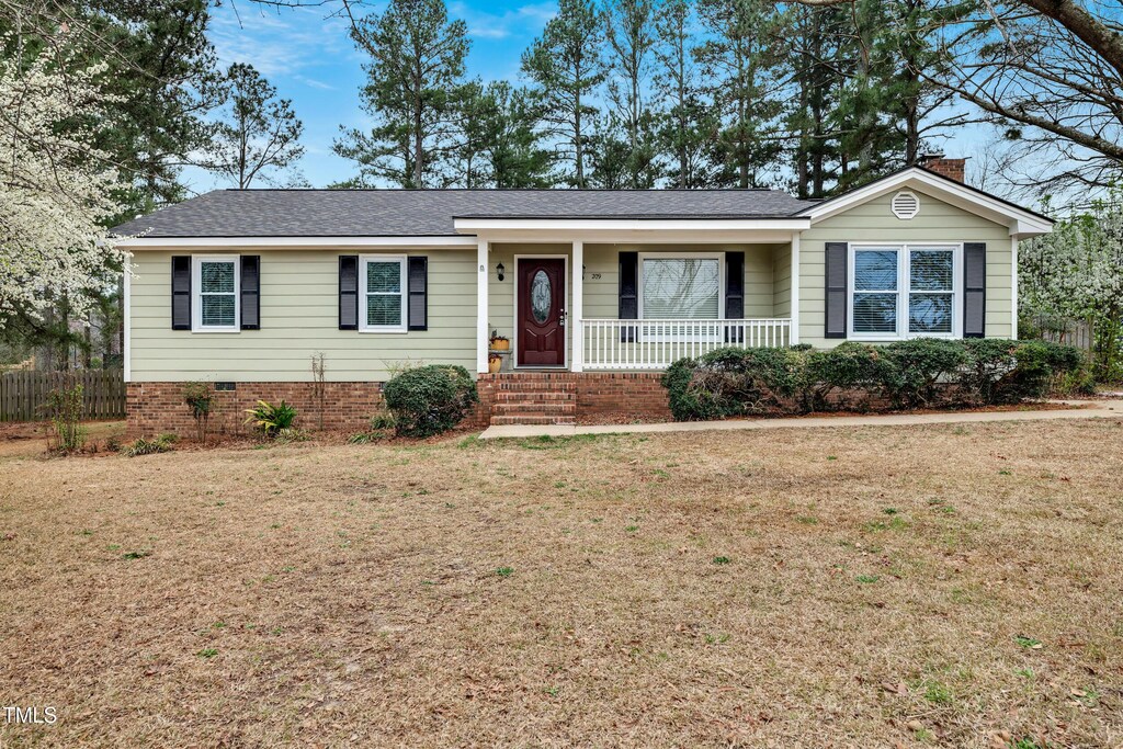 ranch-style home with fence, roof with shingles, covered porch, a chimney, and a front lawn