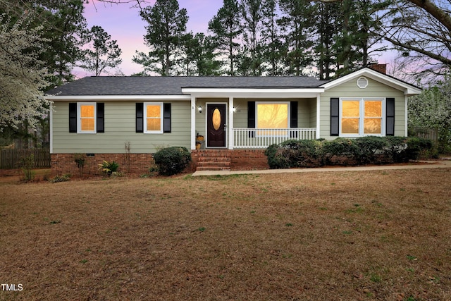 ranch-style house with covered porch, a chimney, a front lawn, and a shingled roof