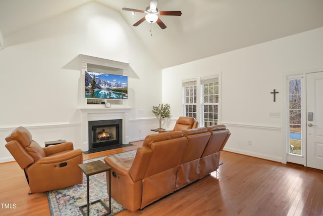 living room with a fireplace with flush hearth, ceiling fan, wood finished floors, high vaulted ceiling, and baseboards