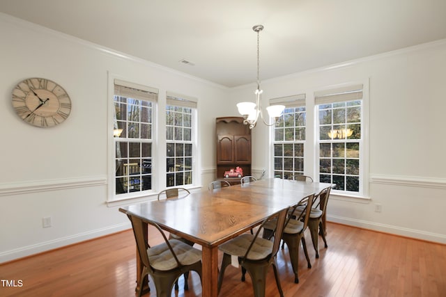 dining area featuring light wood-style flooring, ornamental molding, and baseboards