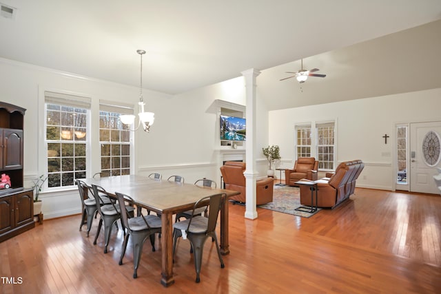 dining area featuring light wood-type flooring, decorative columns, visible vents, and ceiling fan with notable chandelier