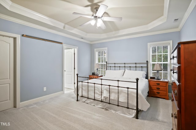 carpeted bedroom featuring a tray ceiling, visible vents, ornamental molding, ceiling fan, and baseboards