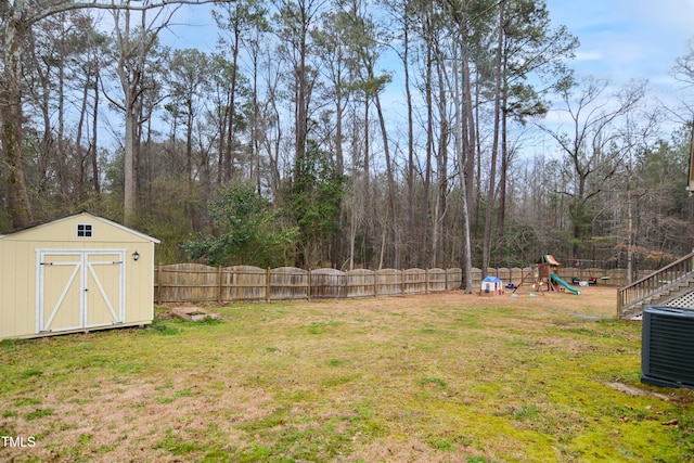 view of yard with a playground, an outdoor structure, a fenced backyard, and a shed