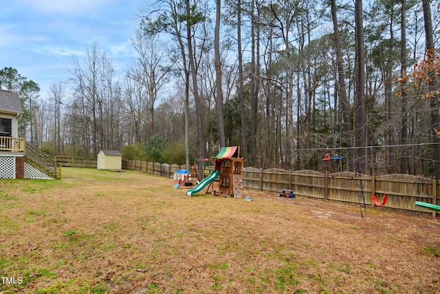 view of yard with an outbuilding, a playground, stairway, a shed, and a fenced backyard