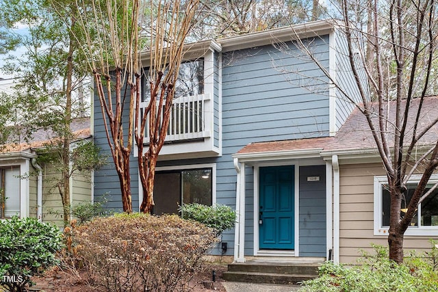 view of front of home with a balcony and roof with shingles