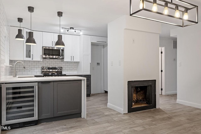 kitchen with beverage cooler, backsplash, stainless steel appliances, and light countertops