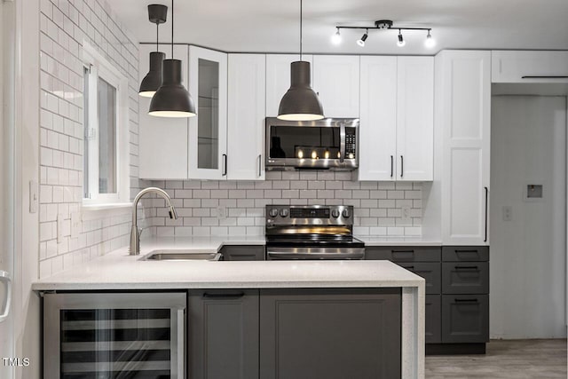 kitchen featuring a sink, backsplash, stainless steel appliances, wine cooler, and glass insert cabinets