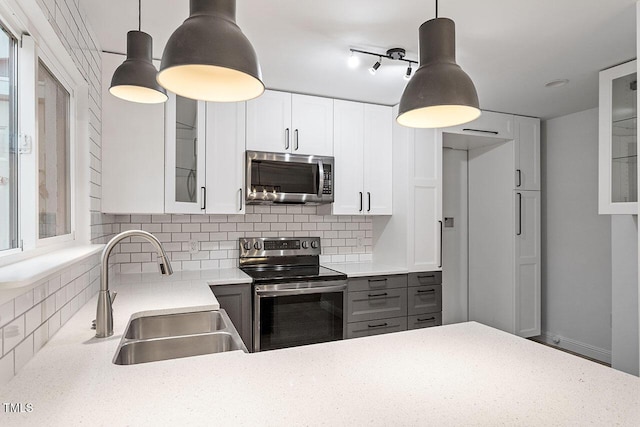 kitchen featuring a sink, stainless steel appliances, glass insert cabinets, white cabinetry, and backsplash