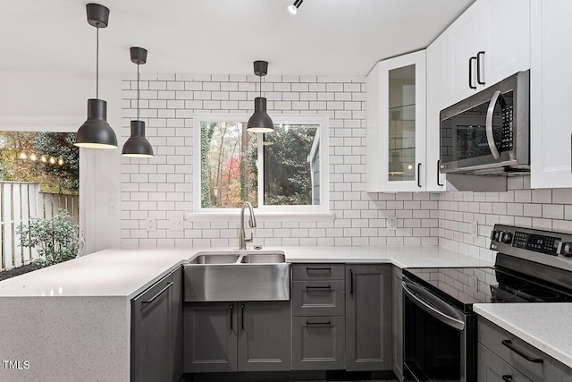 kitchen with a sink, stainless steel appliances, glass insert cabinets, and decorative backsplash