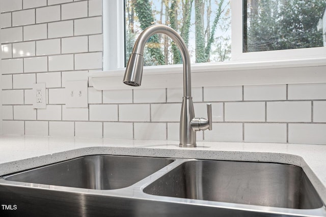 room details with light stone countertops, backsplash, and a sink