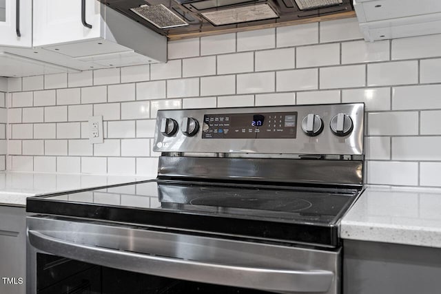 details featuring decorative backsplash, light stone counters, and electric stove