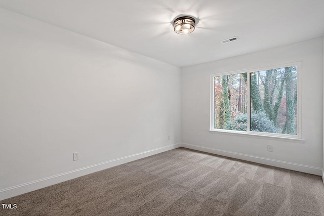 carpeted spare room featuring visible vents and baseboards