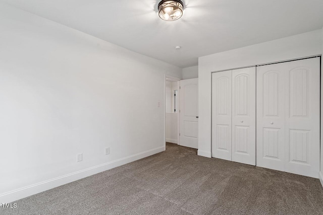 unfurnished bedroom featuring carpet, baseboards, and a closet