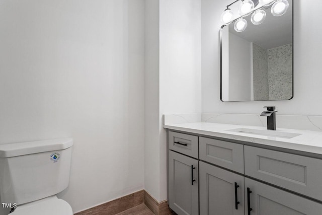 bathroom with toilet, vanity, and wood finished floors