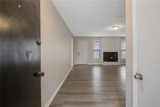 unfurnished living room with a fireplace, baseboards, and wood finished floors