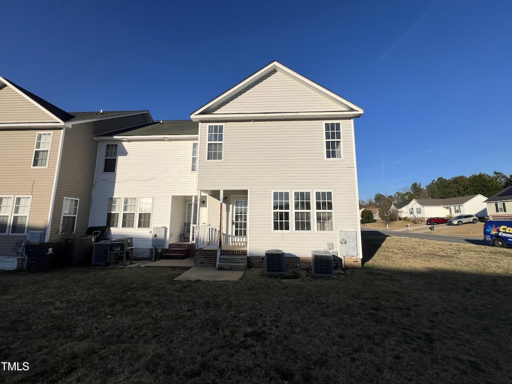 rear view of house with central AC and a yard