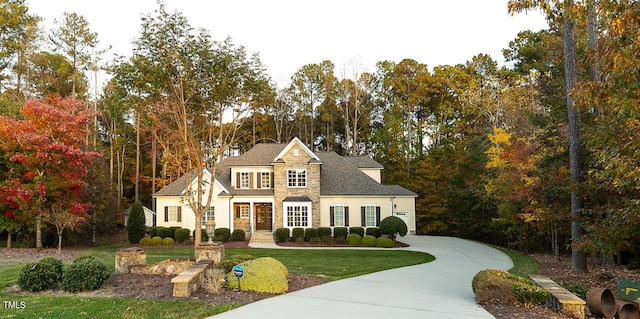 view of front of house featuring a front yard, stone siding, and driveway