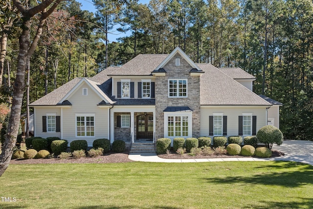 view of front of home with stone siding, a shingled roof, and a front yard