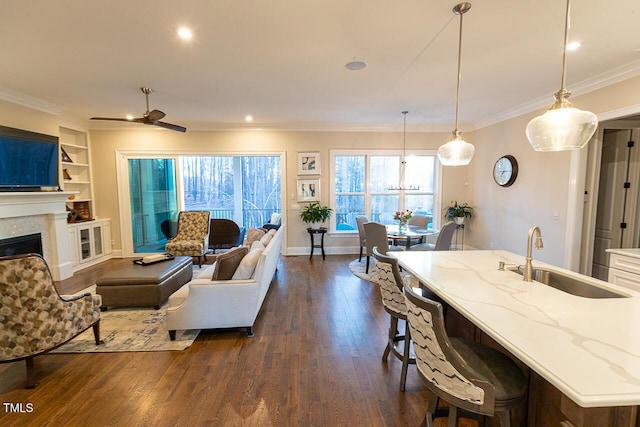 living room featuring built in shelves, baseboards, a fireplace, dark wood-type flooring, and crown molding