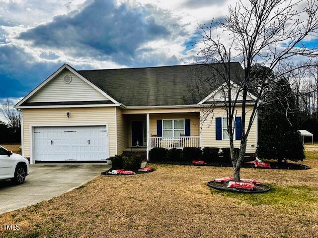 view of front of home featuring an attached garage, a front lawn, a porch, and concrete driveway