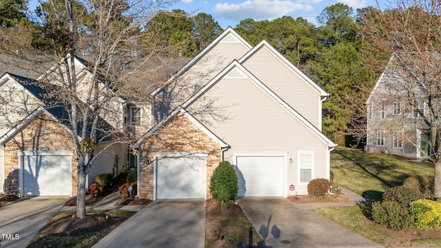 traditional home with stone siding, a front lawn, and concrete driveway