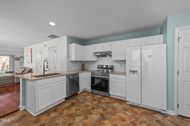 kitchen featuring appliances with stainless steel finishes, open floor plan, a peninsula, under cabinet range hood, and a sink