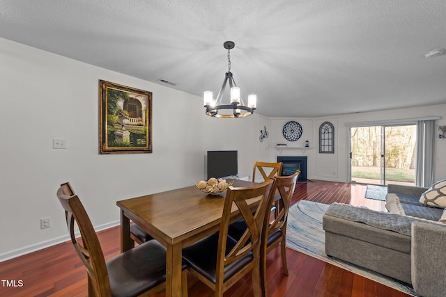 dining room with a textured ceiling, a fireplace with flush hearth, visible vents, baseboards, and dark wood-style floors