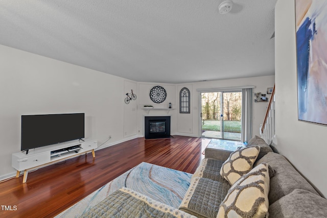 living room with a fireplace with flush hearth, a textured ceiling, and wood finished floors