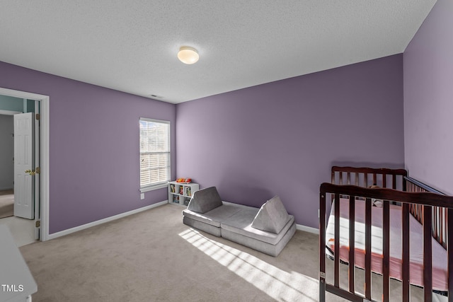 bedroom with a crib, a textured ceiling, baseboards, and carpet flooring