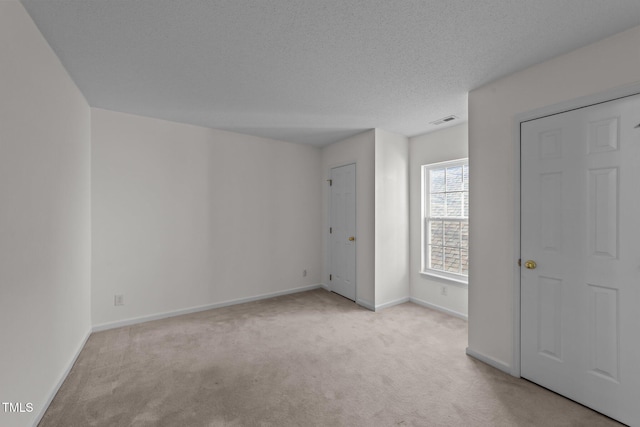 unfurnished bedroom with carpet floors, baseboards, visible vents, and a textured ceiling